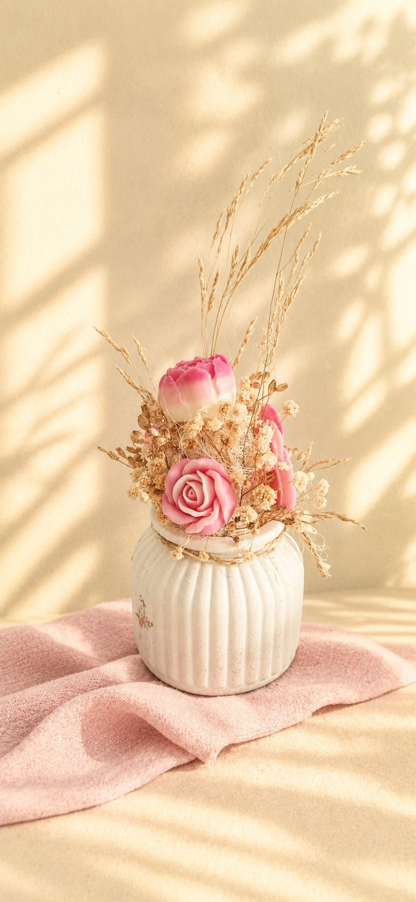 Composition florale en cire végétale rose avec rose mise en avant, orchidée et fleurs séchées dans un vase ivoire strié