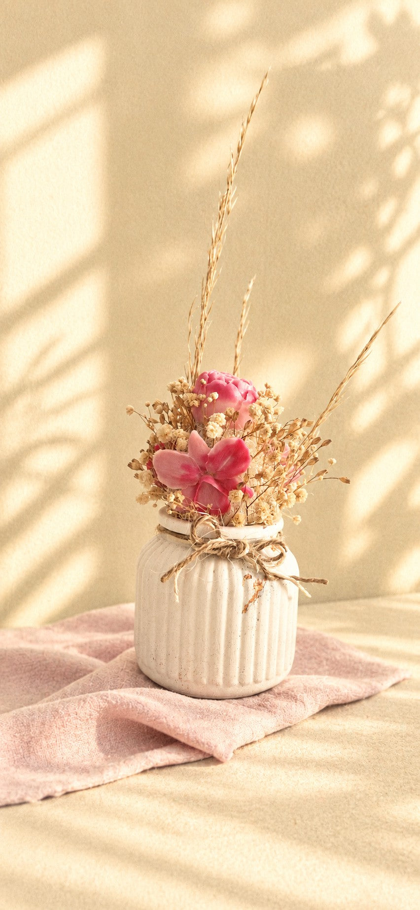 Composition florale en cire végétale avec rose fuchsia, orchidée rose et fleurs séchées dans un vase ivoire