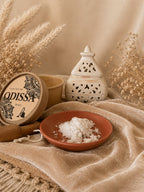 Poudre aspirateur parfumée Odissa Velours – packaging kraft ouvert, poudre blanche sur coupelle terracotta et décor naturel beige