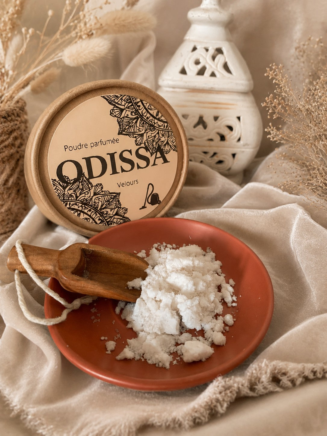 Poudre aspirateur parfumée Odissa Velours – boîte kraft ouverte avec poudre blanche sur coupelle terracotta et cuillère en bois