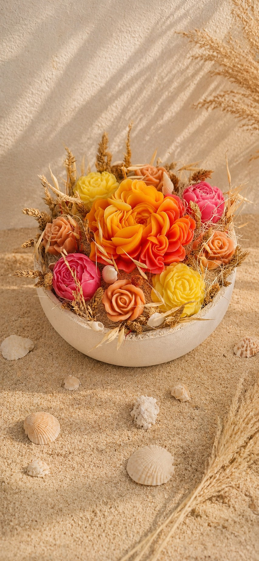 Composition florale Rivage d'Été en cire végétale, vue de face avec la grande pivoine orange, les pivoines fuchsia et les roses pêche dans la vasque couleur sable