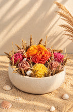 Composition florale Rivage d'Été en cire végétale, vue rapprochée sur le dahlia jaune soleil, la pivoine orange et les pivoines fuchsia parmi les fleurs séchées