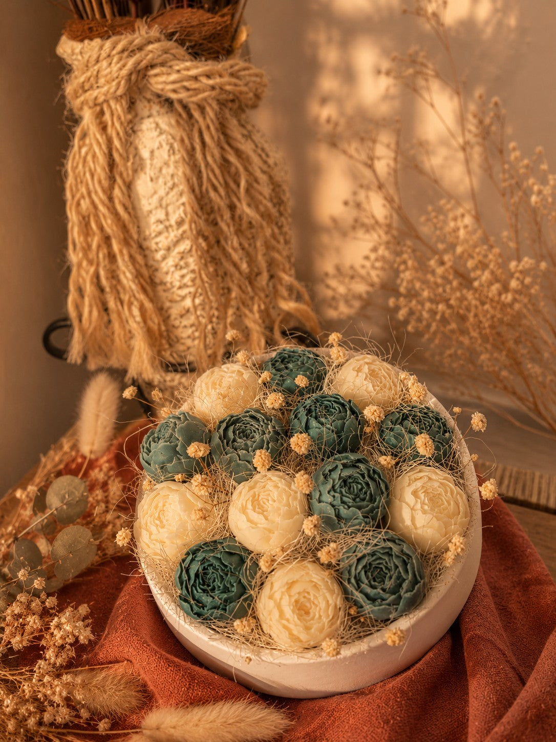Composition florale en cire végétale Odissa – roses ivoire et bleu-vert dans vasque en résine minéral de gypse avec vase en corde et fleurs séchées