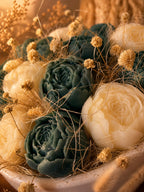 Gros plan sur les roses en cire végétale Odissa – pétales sculptés bleu-vert et ivoire avec fleurs séchées dorées