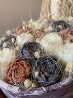 Gros plan sur les roses en cire végétale Odissa – pétales sculptés terracotta et gris ardoise avec fleurs séchées