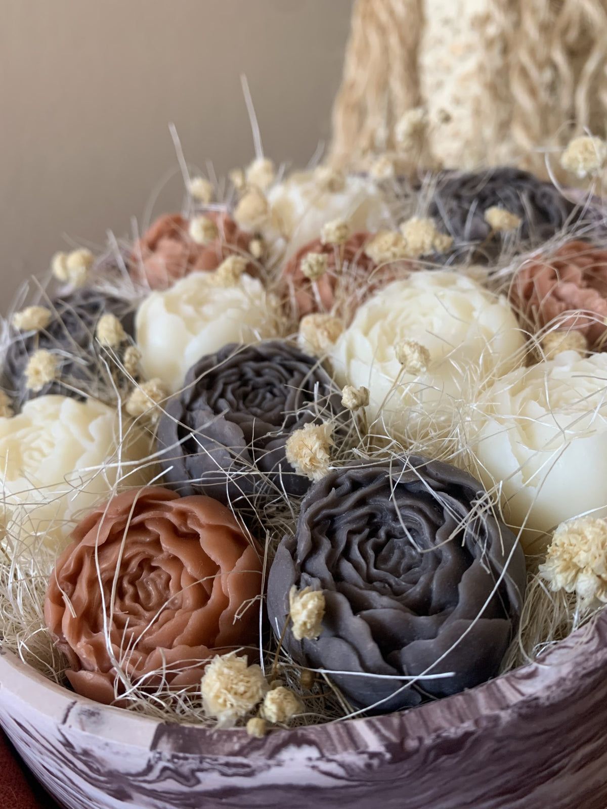Gros plan sur les roses en cire végétale Odissa – pétales sculptés terracotta et gris ardoise avec fleurs séchées