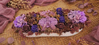 Composition florale Mauve Précieux en cire végétale, vue rapprochée dans une vasque mauve avec roses mauves et fleurs séchées