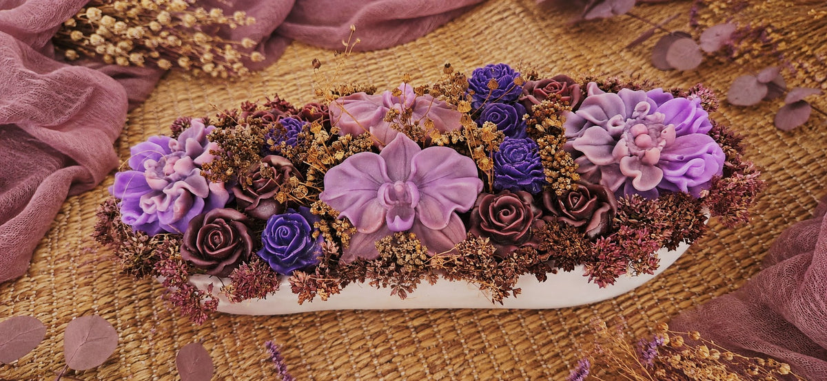 Composition florale Mauve Précieux en cire végétale, vue rapprochée dans une vasque mauve avec roses mauves et fleurs séchées