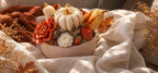 Vue de dessus de la composition Éclat d'Automne : citrouilles blanches et orange, courges dorées et roses crème en cire végétale