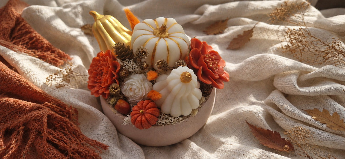 Composition d'automne Odissa posée sur un plaid beige avec plaid terracotta et feuilles séchées