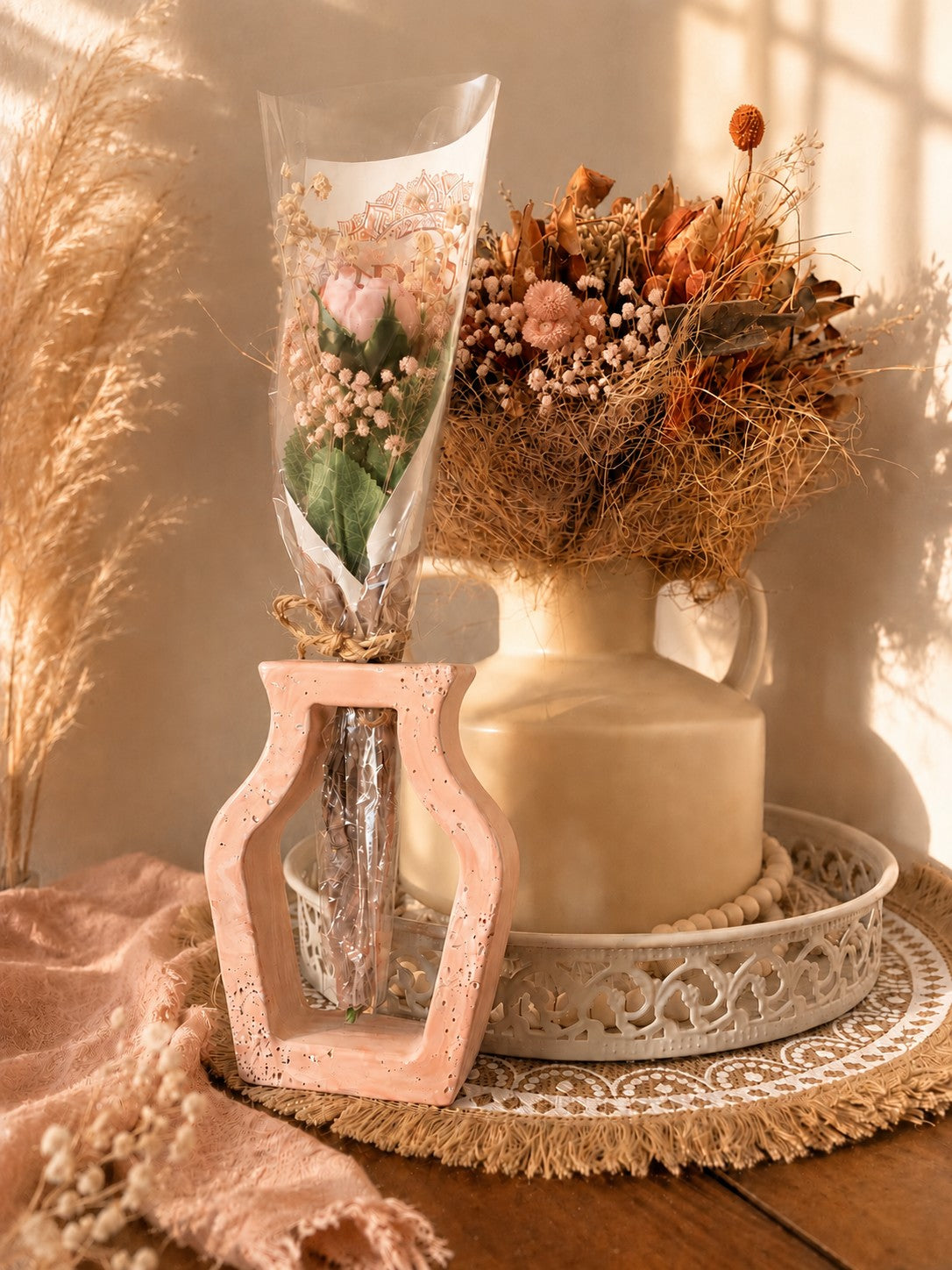 Vase ajouré terracotta poudré avec une rose en cire végétale, dans une ambiance de fleurs séchées