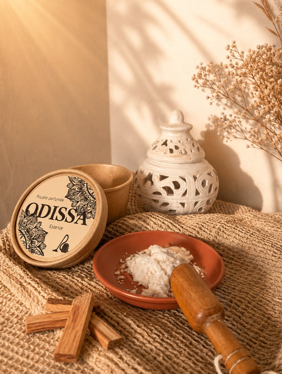Boîte ronde Odissa Poudre Parfumée Essence avec couvercle à motifs mandala, coupelle en terre cuite remplie de poudre blanche et brûleur céramique blanc ajouré sur fond beige chaud