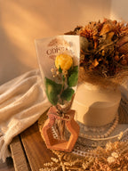 Vase ajouré en résine minérale terracotta Odissa avec rose en cire végétale jaune, présenté sur plateau blanc décoré de fleurs séchées