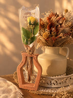 Vase ajouré terracotta Odissa avec sa rose en cire végétale jaune emballée, mis en scène avec un bouquet de fleurs séchées automnales